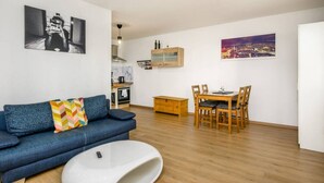 A modern living room with a blue sofa, a white coffee table, and a dining area with wooden chairs and a table. - Arbio I Spacious Apart near Auensee (Leipzig)