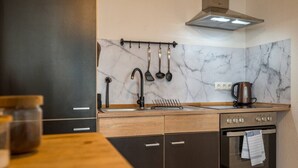A modern kitchen with a marble backsplash, wooden cabinets, a stainless steel range hood, and a kettle on the countertop. - Arbio I Spacious Apart near Auensee (Leipzig)