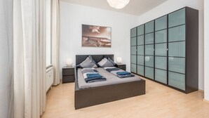 Un dormitorio moderno con una cama grande, un armario de vidrio y una lámpara colgante.