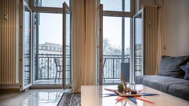 Una sala de estar moderna con un sofá, una mesa de centro y vistas a un balcón nevado.
