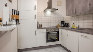 A modern kitchen with white cabinets, a stainless steel range hood, and a built-in oven. - Arbio I Quiet Apart in Sudvorstadt (Leipzig)