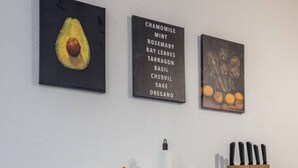 A kitchen area with a white countertop, a knife block, and three framed items on the wall. - Arbio I Quiet Apart in Sudvorstadt (Leipzig)