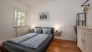 A bedroom with a bed, two bedside tables, a radiator, a window, a wall-mounted picture, and a wardrobe. - Arbio I Quiet Apart in Sudvorstadt (Leipzig)
