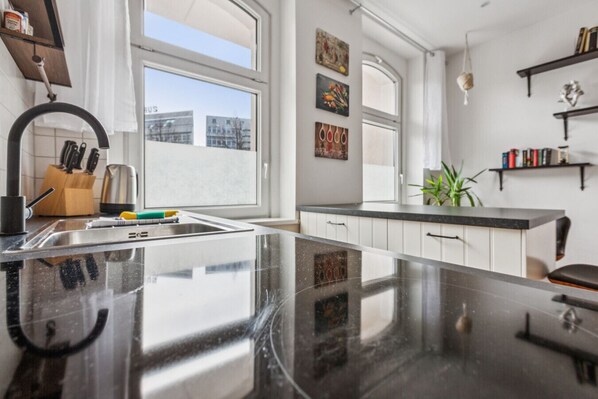 A modern kitchen with a large island, white cabinetry, and a view of buildings through large windows.