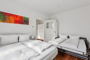 A hotel room with two beds, a wardrobe, a door, and a colorful abstract painting on the wall. - Arbio I Retro Apart in Leipzig center (Leipzig)