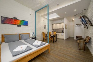 Een moderne hotelkamer met een houten bed, een klein bureau, een zithoek en een keuken.