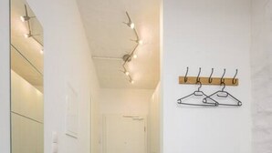 A hallway with a wooden floor, a coat rack, and a small wooden cabinet with a black tray. - Arbio I Industrial Studio in Leipzig Bayerischer (Leipzig)
