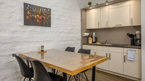 A modern kitchen with a dining table and chairs, a painting on the wall, and cabinets. - Arbio I Industrial Studio in Leipzig Bayerischer (Leipzig)