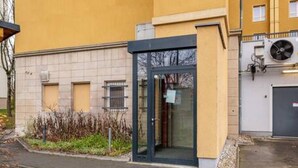 A building with a glass entrance, a small garden area, and a paved walkway. - Arbio I Industrial Studio in Leipzig Bayerischer (Leipzig)