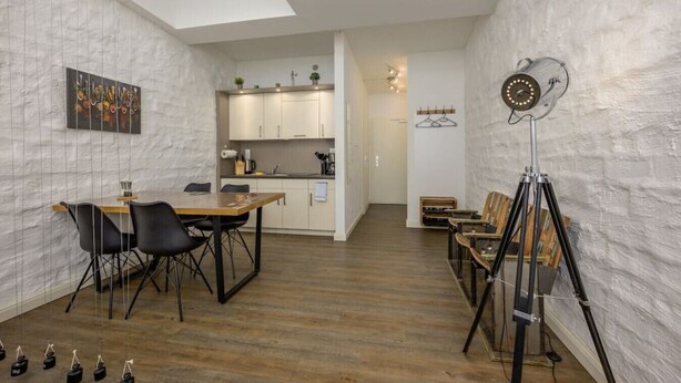 A modern interior with a dining area, kitchen, and a studio space with a tripod and lights. - Arbio I Industrial Studio in Leipzig Bayerischer (Leipzig)