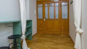Un couloir étroit avec un plancher en bois, une porte en bois dotée de panneaux de verre et une chaise noire.