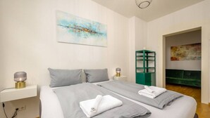 Une chambre d’hôtel avec deux lits, un meuble de rangement vert et un tableau accroché au mur.