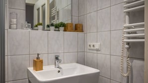 A bathroom with a white sink, a wooden soap dispenser, a mirror, and a towel rack. - Arbio I Retro Apart near Grassi Museum (Leipzig)