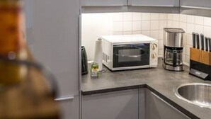 A modern kitchen with grey cabinets, a built-in oven, a coffee maker, and a knife block.