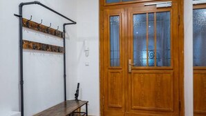 A hallway with a wooden door, a coat rack, and a bench.