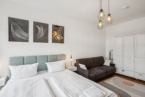 Een moderne slaapkamer met een bed, een bank en een kledingkast.