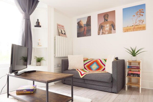 A living room with a grey sofa, a wooden coffee table, a television, and a bookshelf with books. - Summer Family Terrace Apartment - Central Location (London)