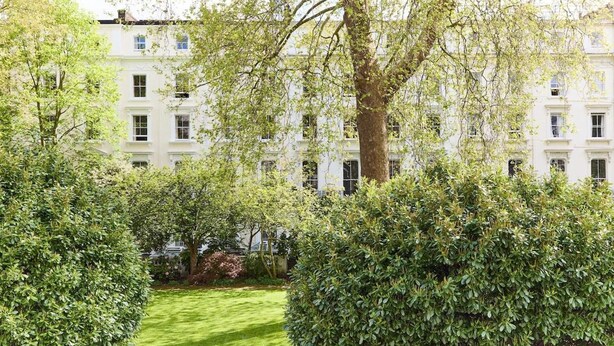 Un grand immeuble à étages, doté d’un jardin bien entretenu à l’avant.