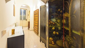 Un couloir avec un mur à motifs à carreaux, un grand tableau représentant des fruits et un comptoir moderne.