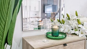 A modern bathroom with a mirror, a green candle holder, and white flowers. - Blissful Bradford Apartment - City Center Gem (Bradford)