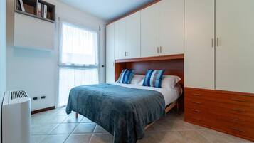Un dormitorio con cama, armario y ventana.