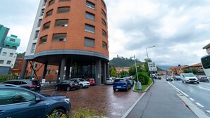 Ein mehrgeschossiges Gebäude mit einer gewölbten Fassade, einem Parkplatz mit Autos und einem Schild mit der Aufschrift "SPAZIO LIBERO".