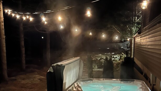 A hot tub on a wooden deck with string lights overhead. - Luxury Poconos Chalet - Hot Tub, Fire Pit, Wineries , Breweries & Pet-Friendly!! (Albrightsville)