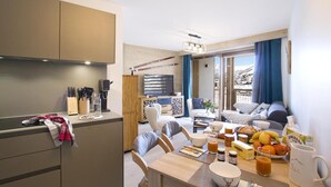 Une cuisine moderne avec un coin repas, un téléviseur et une vue sur un paysage enneigé.