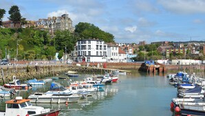 A harbor with various boats docked, a building with multiple windows, and a stone wall. - Minutes from Folkestone Central Station and modern flat with three bedrooms. (Cheriton, near Folkestone)