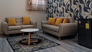 Un salon moderne avec deux canapés, une table basse et un mur orné d’un motif.