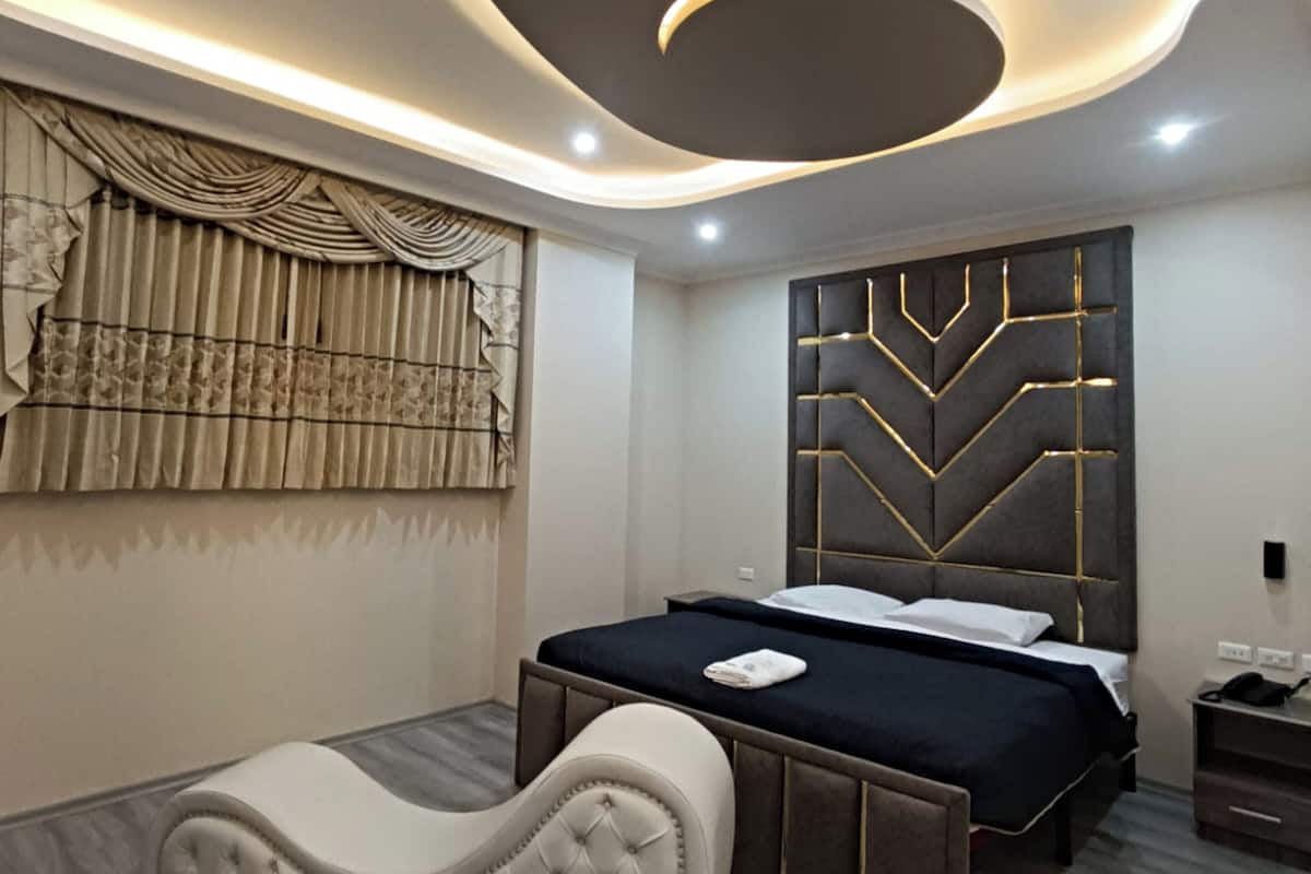A modern bedroom with a bed, a headboard with geometric patterns, a tufted headboard, and a wall-mounted light fixture.