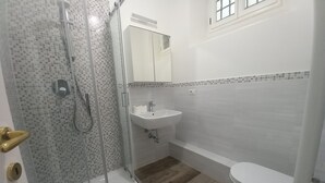 A bathroom with a glass-enclosed shower, a sink, a toilet, and a bathtub.