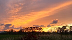 A sunset over a rural landscape with trees silhouetted against the sky. - Private room, in a quiet, leafy setting.  (ploneour lanvern)