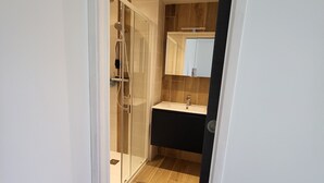 A modern bathroom with a glass shower enclosure, a vanity with a dark countertop, and a mirror above the sink. - Private room, in a quiet, leafy setting.  (ploneour lanvern)