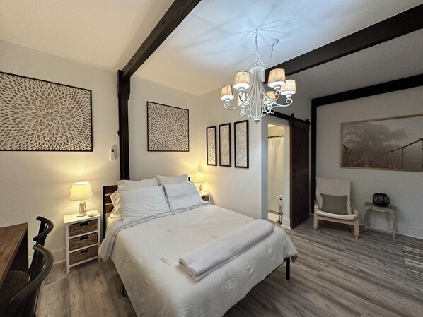 Ein Schlafzimmer mit einem großen Bett, einer Chandelüster und Kunstwerken an den Wänden.