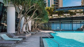 Un área de piscina en la azotea con sillones de descanso y una piscina grande.