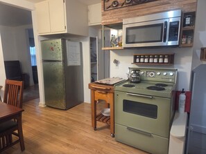 A kitchen with a refrigerator, microwave, stove, and wooden cabinets.