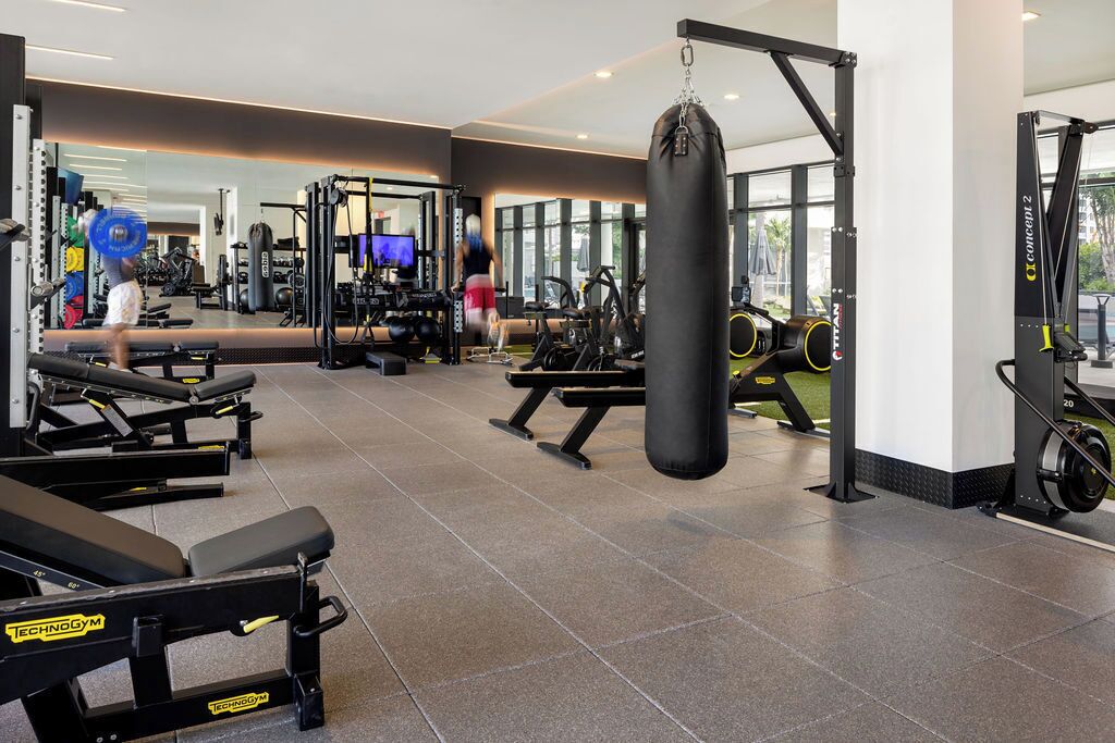 A gym with various exercise equipment, including benches, a punching bag, and weightlifting stations.