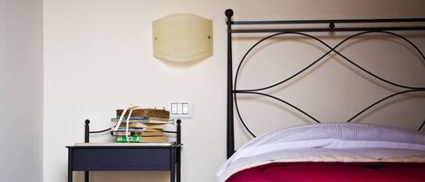 Une chambre à coucher avec un lit, une table de chevet avec des livres et une lampe fixée au mur.