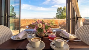 Une table dressée pour deux personnes, avec des tasses à café, un vase de fleurs et une assiette à dessert.