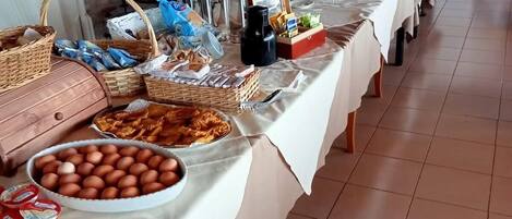 A buffet table with various food items and beverages, including eggs, pastries, and condiments.