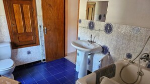 Een badkamer met toilet, wastafel, bad en een houten deur.