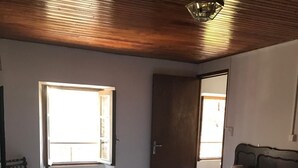 Een slaapkamer met een bed, een stoel, een raam en een deur.