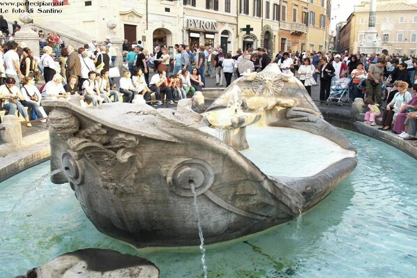 A public fountain with a large stone sculpture of a fish, surrounded by a crowd of people. - Stylish Apartment in Historic Rione Celio (Roma)