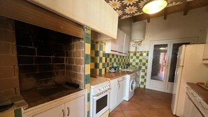 A compact kitchen with a stove, washing machine, and a sink. - House in front of the sea and nature of Fleury (Fleury)