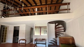 A spacious loft with a dining area, a staircase, and a cozy seating area. - House in front of the sea and nature of Fleury (Fleury)