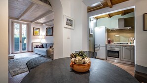 A modern kitchen with a built-in oven, a stainless steel refrigerator, and a dining area with a round table.