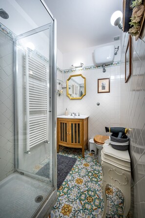 Un baño con cabina de ducha de vidrio, un armario de madera, un lavamanos y un inodoro.