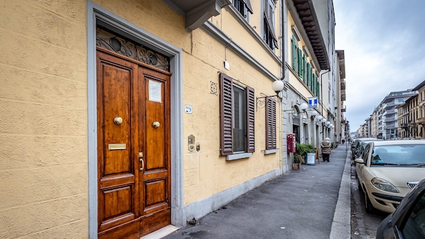 Un vicolo stretto con un'antica porta in legno e persiane su un edificio.