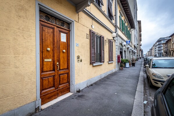 A narrow street with a wooden double door and shutters on a building. - YiD Masaccio (Florence)